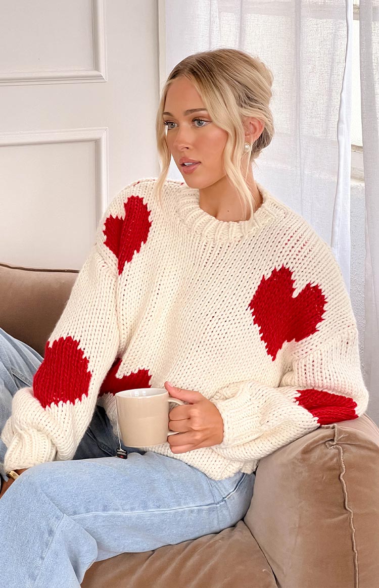 Cream chunky knit sweater with large red heart patterns on the front and sleeves, highlighting the textured knit