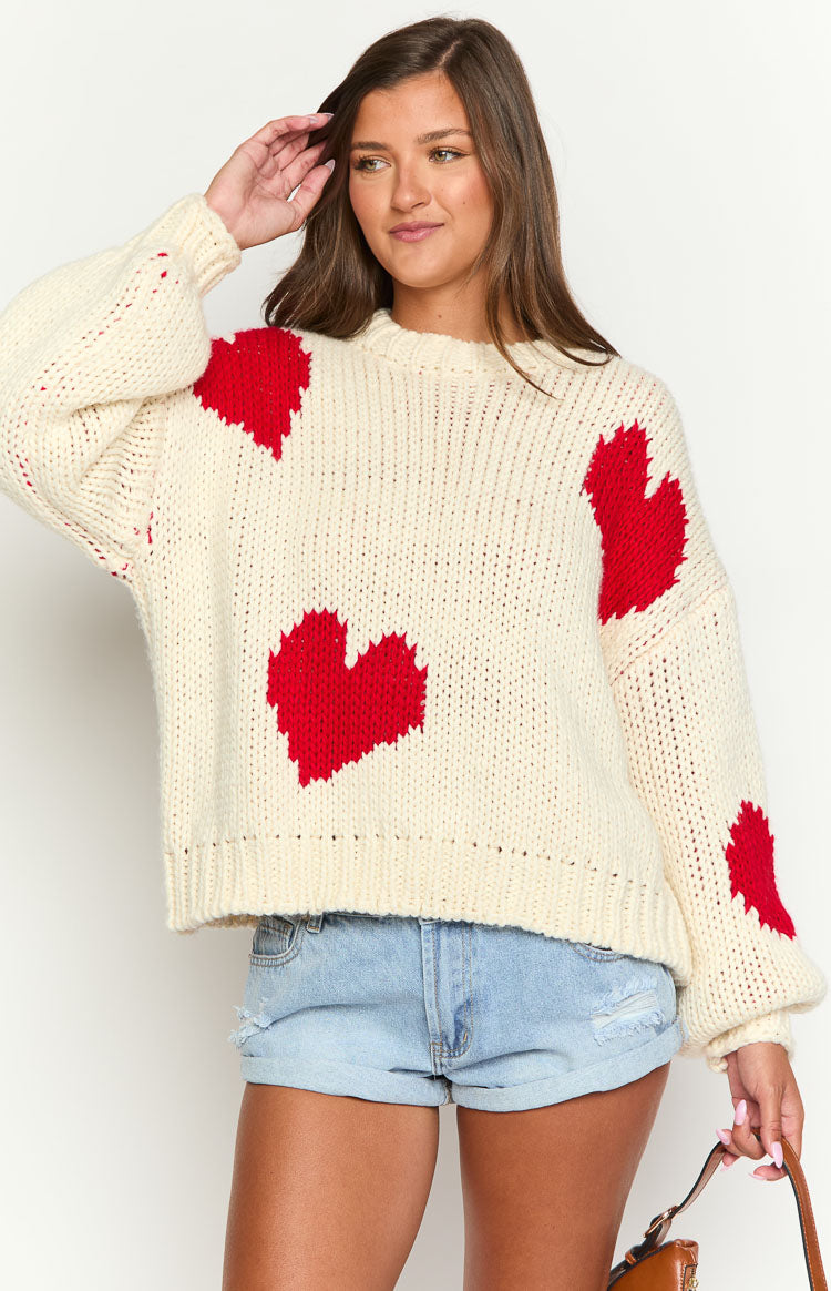 Close-up of the cream chunky knit sweater with red heart pattern and crew neckline