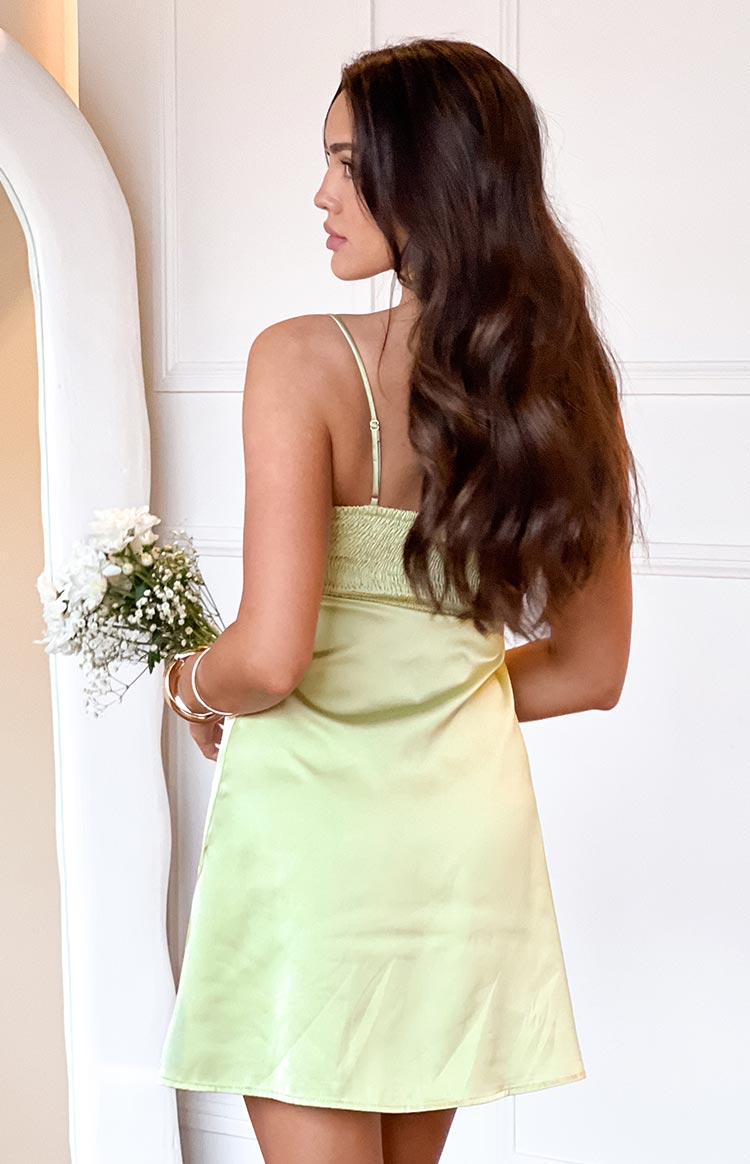 Rear view of a sage satin mini dress showing the smocked upper back and thin adjustable spaghetti straps