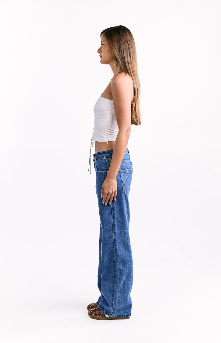 Side view of mid wash blue low waist baggy leg jeans with a wide silhouette