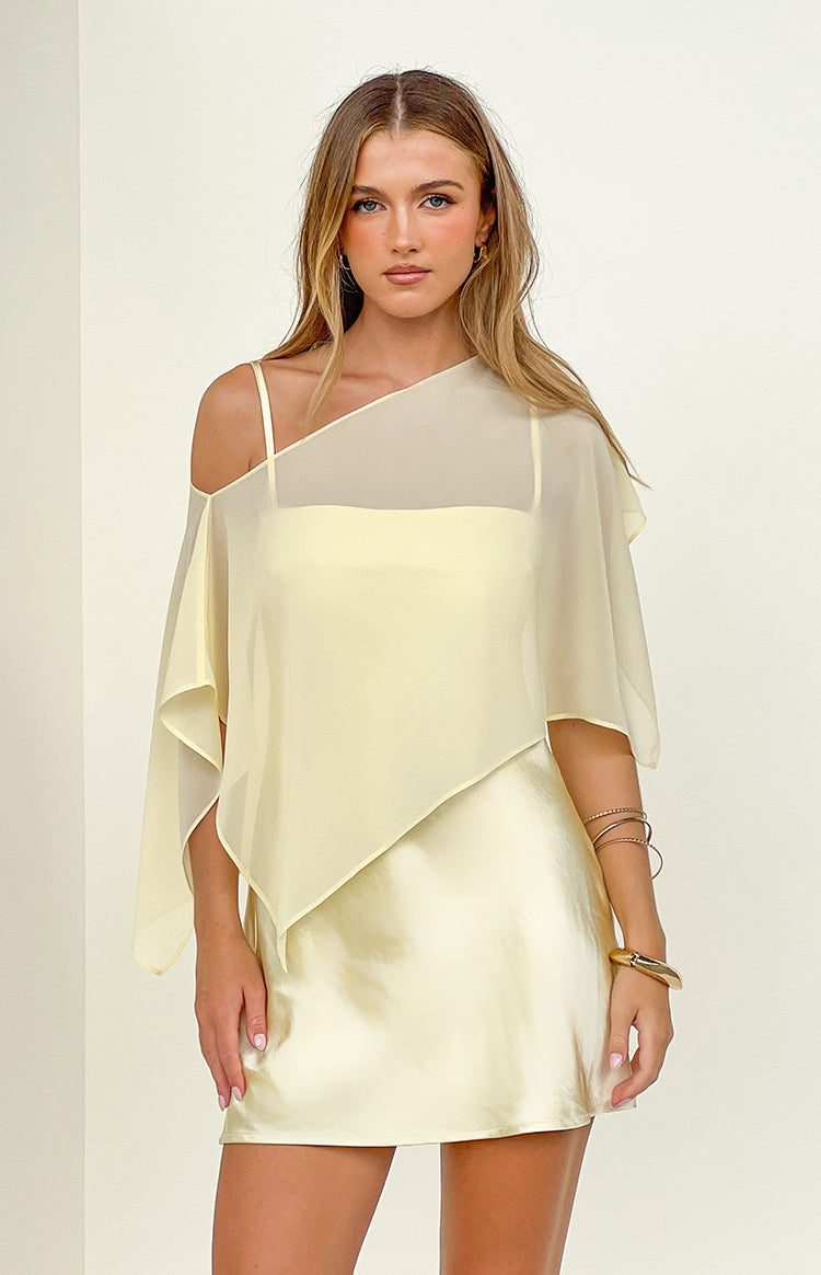 Asymmetrical yellow sheer chiffon cape with one shoulder exposed and a soft flowing drape