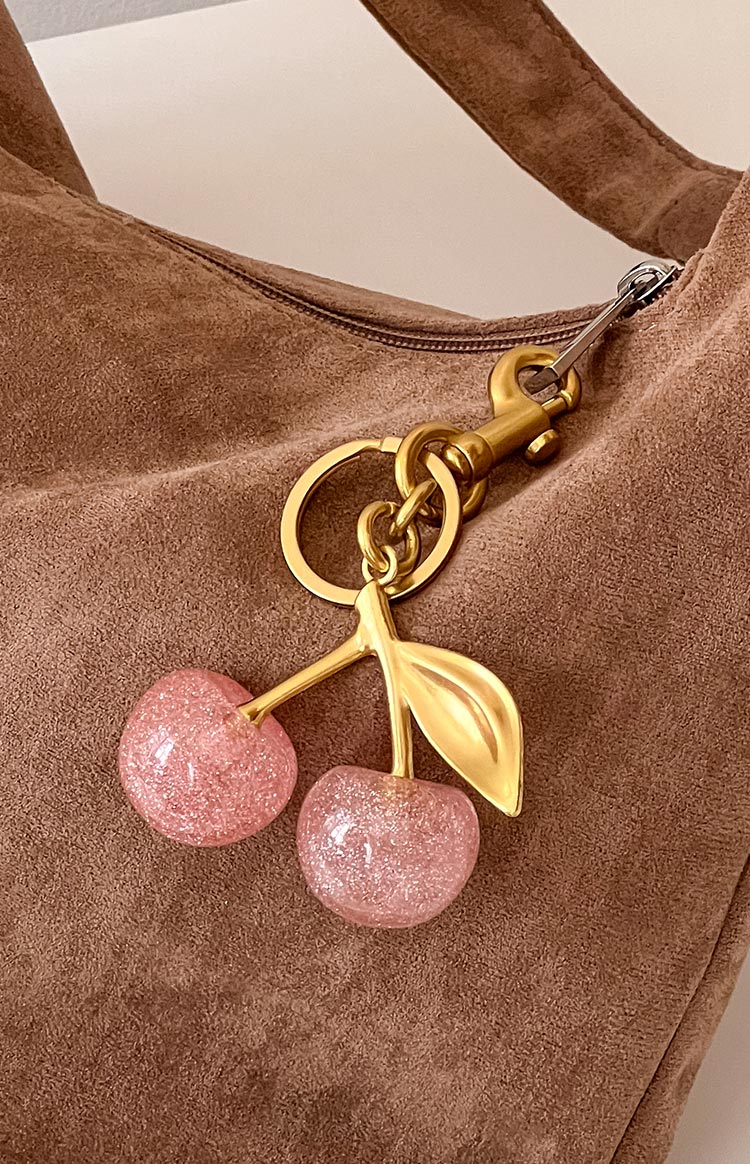 Detail shot of the pink glitter resin cherries, gold stem, leaf, and gold-toned lobster clasp