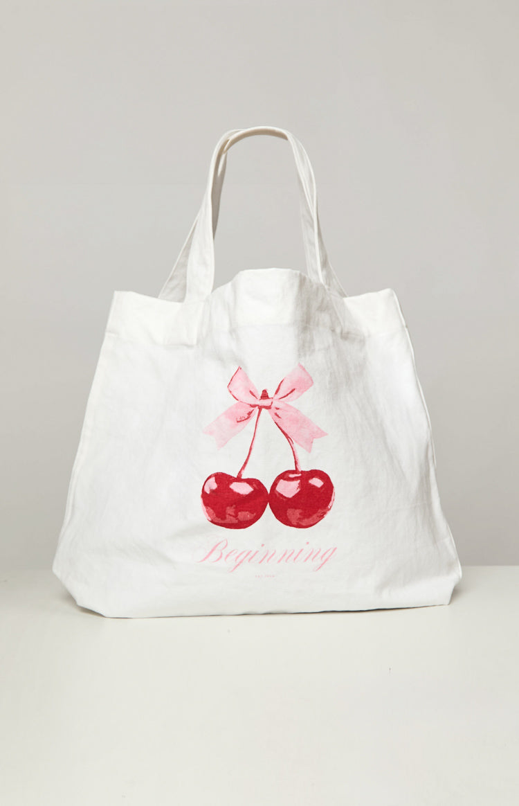 Front view of a white tote bag featuring a red cherry graphic with a pink bow and 'Beginning' text
