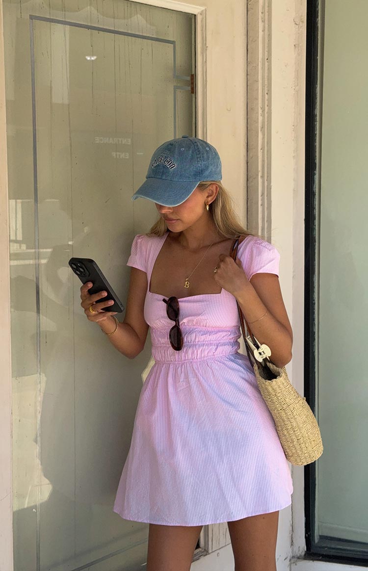 Front view of a light pink and white striped mini dress with a square neckline, cap sleeves, and shirred waist