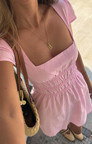 Close-up of a light pink and white striped mini dress with a square neckline and ruched bodice.