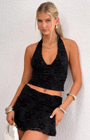 Detail shot of the black velvet mini skirt showing the embossed floral pattern and ruffled hem