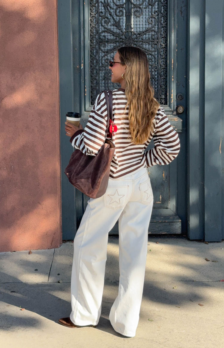 Rear view of white low-rise denim jeans with star embroidery on the back pockets and a wide-leg fit