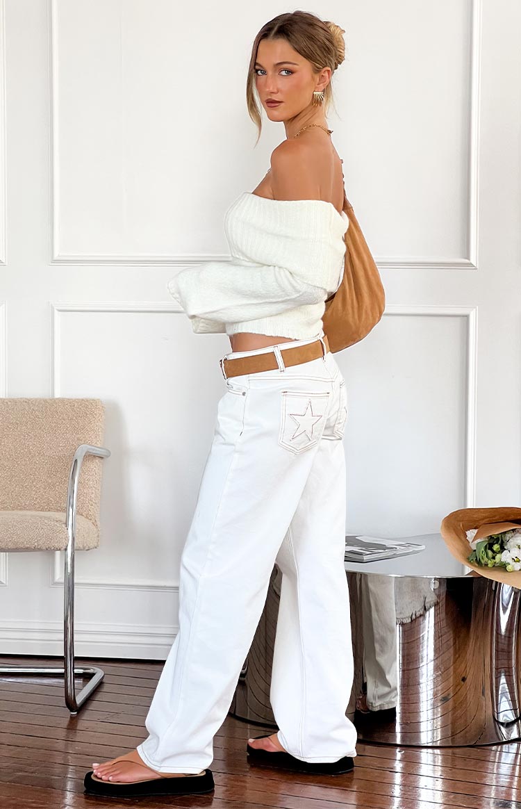 Side view of white low-rise wide-leg jeans with star embroidery on the back pocket and contrast stitching