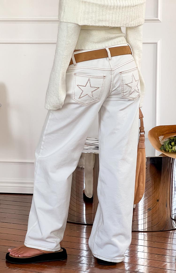 Rear view of white denim low rise jeans with star-shaped stitching on back pockets and contrast brown topstitching