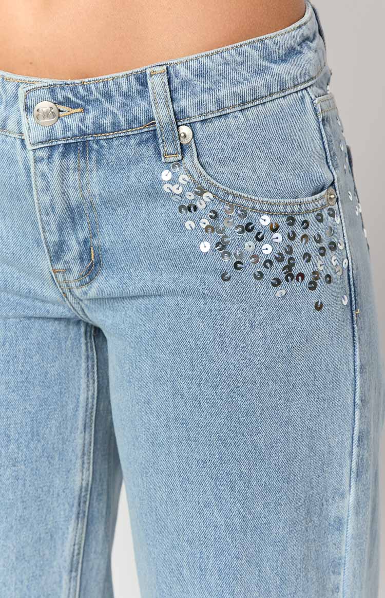 Close-up of the front pocket of light wash denim jeans with silver sequin embellishments