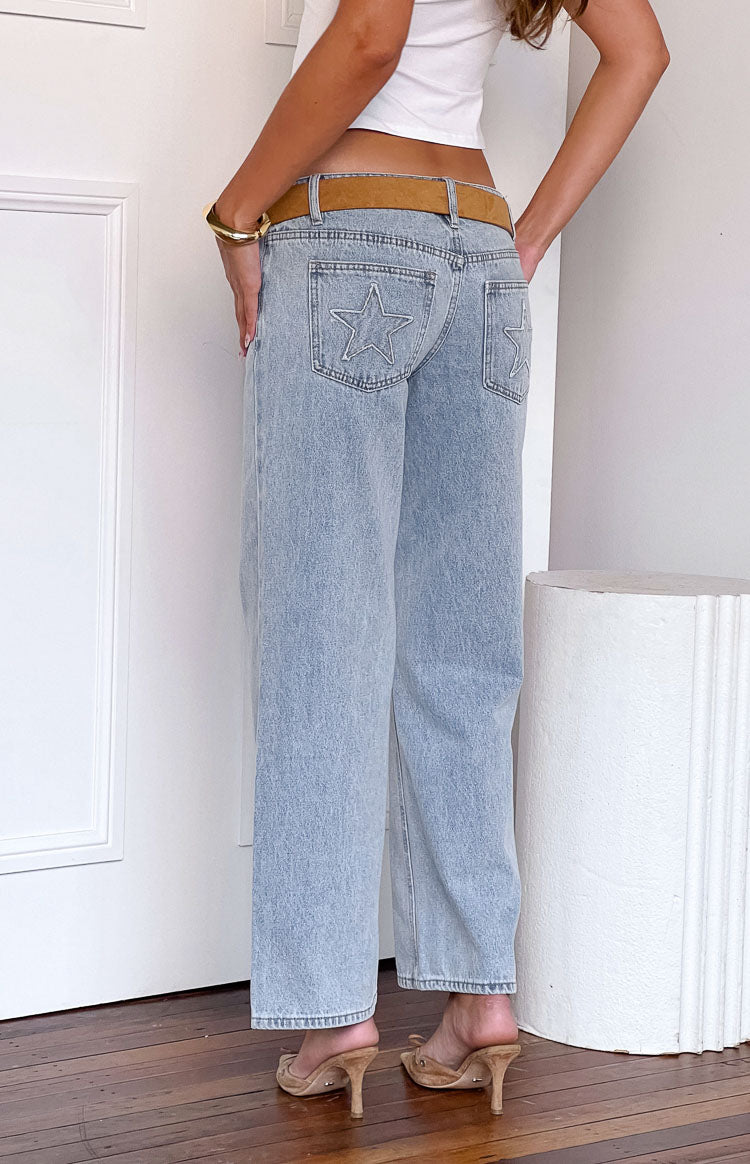 Rear view of light wash denim low rise jeans with star embroidery on the back pockets