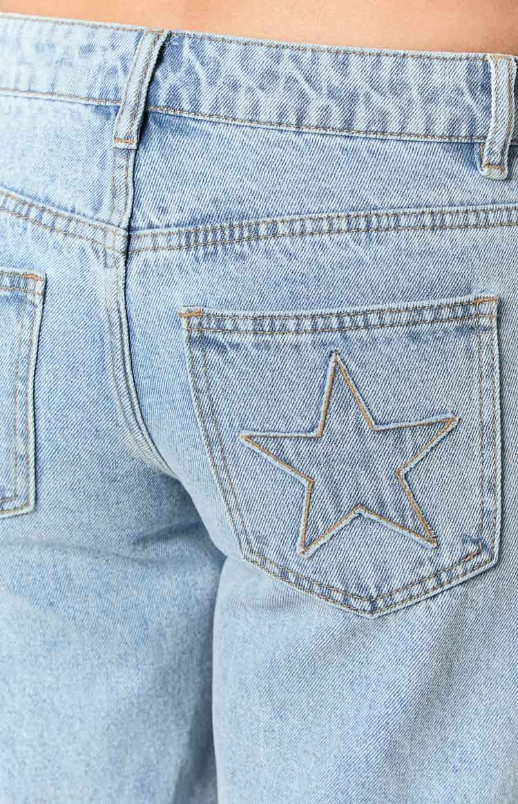 Detail shot of the back pocket on light wash denim jeans with a star outline stitched in tan