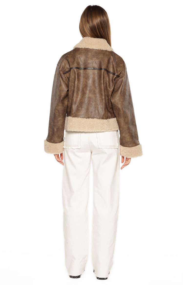 Rear view showing the brown faux leather aviator jacket with wide beige shearling collar, cuffs, and hem