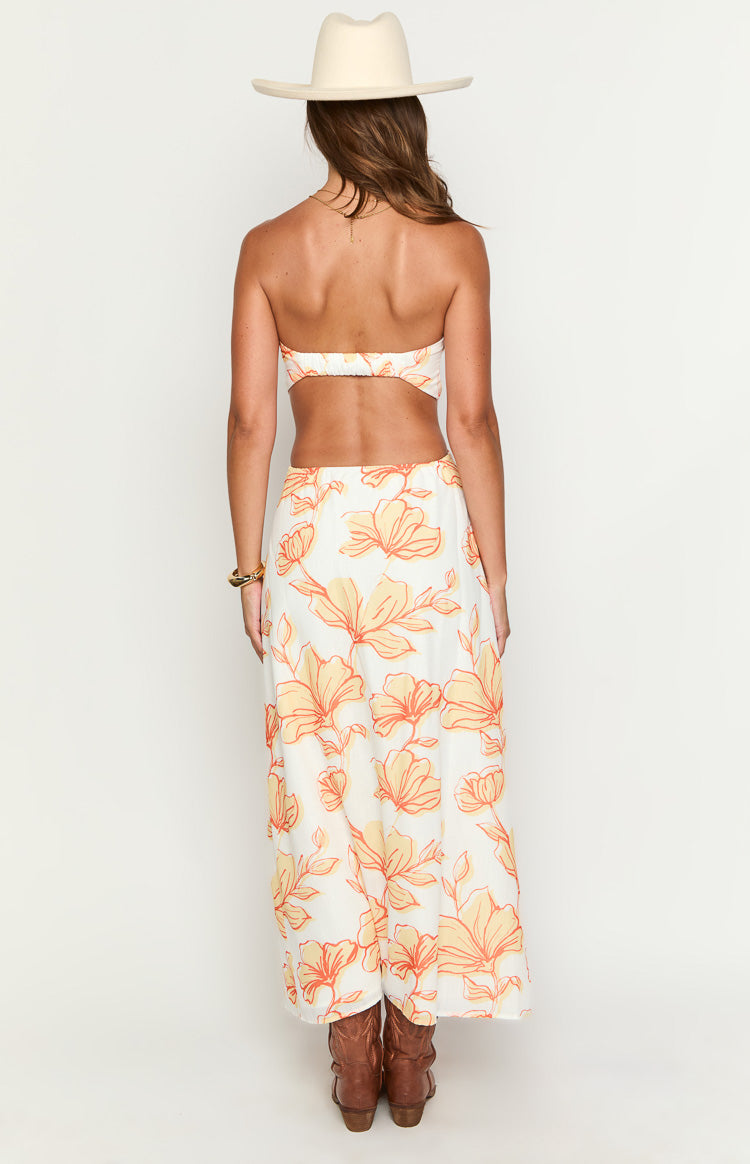 Rear view of a white strapless maxi dress with orange floral print, showing the elasticated back and waist cutout