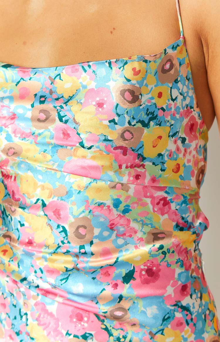 Close-up of the side ruching detail on the vibrant pink, blue, and yellow floral satin mini dress