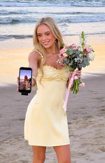 Yellow satin mini dress with flower detail on the straps and sweetheart neckline, ruched bust
