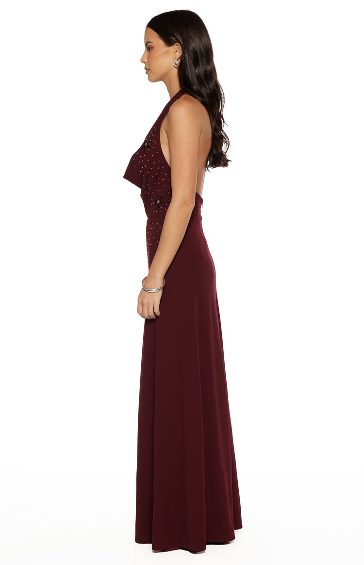 Side view of a burgundy crepe maxi dress showing the draped halter neckline, beaded bodice, and open back