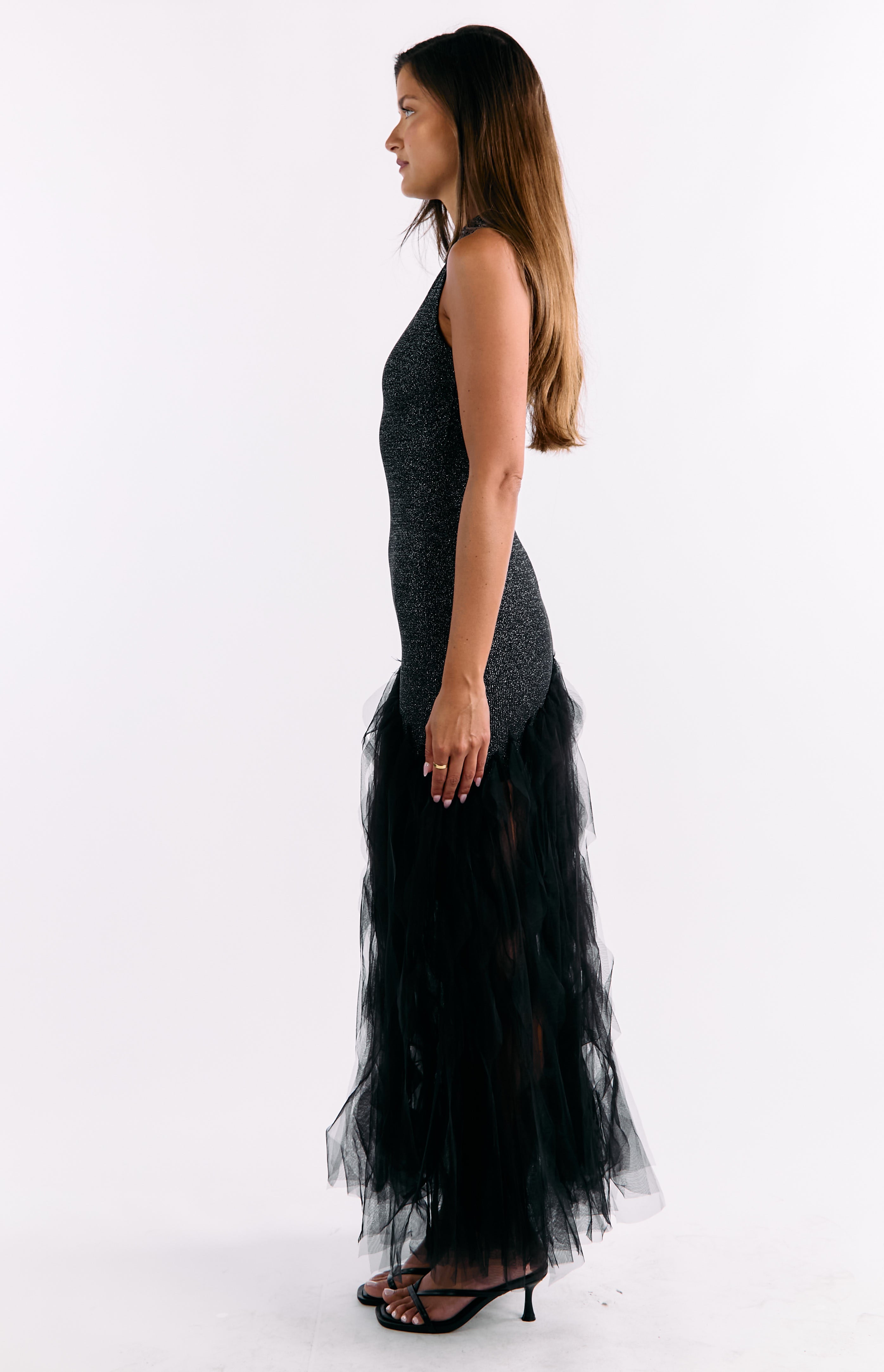 Side view of the black sequin maxi dress, highlighting the fitted silhouette and layered tulle ruffle skirt