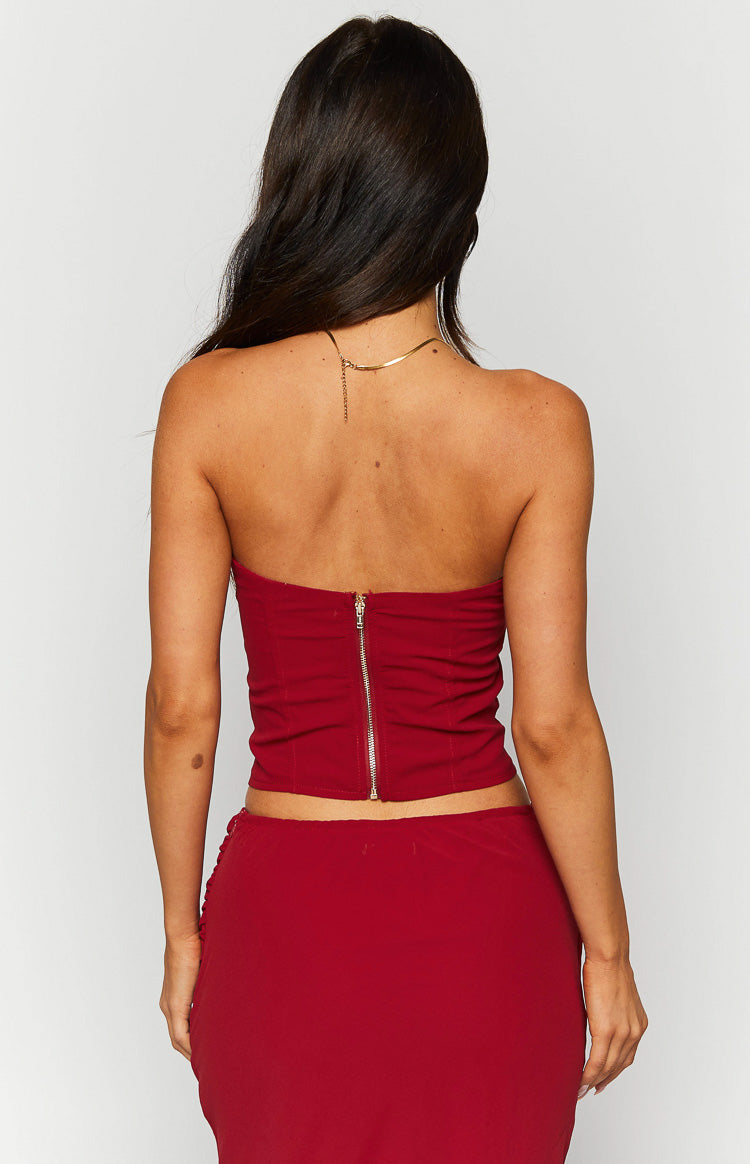 Rear view of a crimson red strapless corset top with a gold zipper down the center back and ruched detailing