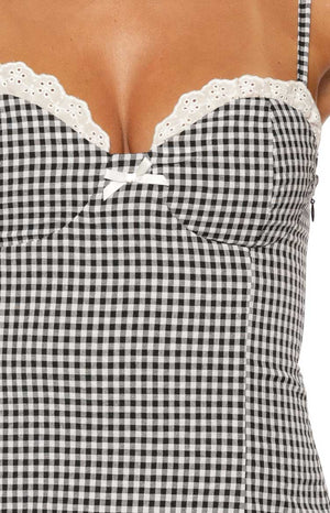 Close-up of the black gingham mini dress showing white broderie anglaise lace trim, a small white bow, and side zipper