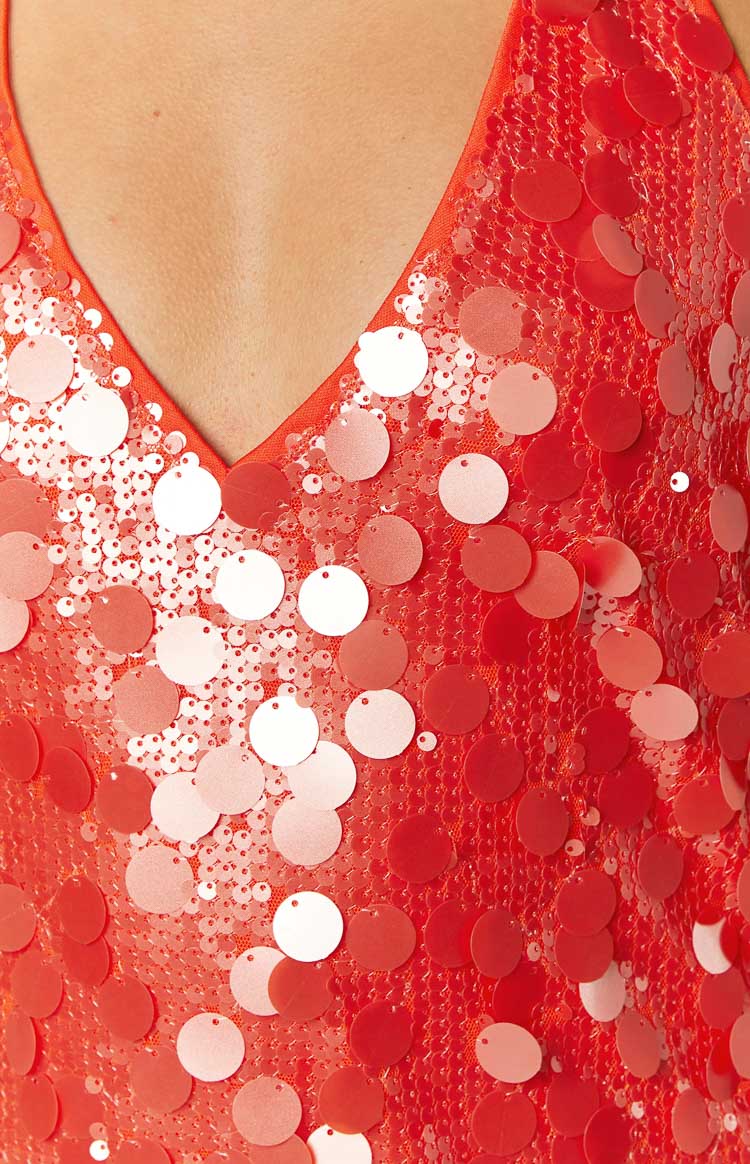 Close-up of the orange sequin V-neckline, featuring various sizes of orange and iridescent sequins