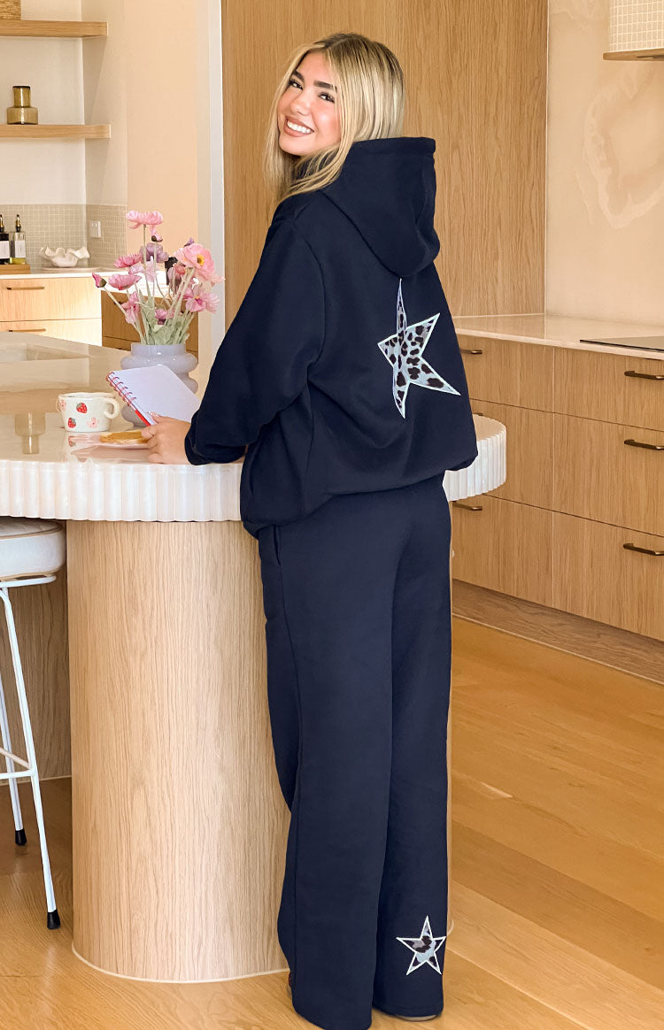 Navy track pants with a white outline star and leopard print detail on the lower leg