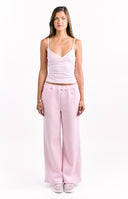 A pair of light pink wide-leg flared sweatpants perfectly worn as part of a matching set. Our pants are made of a soft fleece or jersey material.
