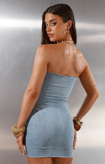 Rear view of a light wash denim strapless mini dress with a raw frayed edge neckline and hem