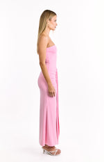 Side view of a fitted pink strapless maxi dress with ruched side detail and a long skirt with a side slit
