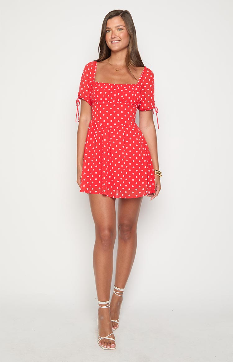 Red polka dot mini dress with a square neckline, cinched waist, and short puff sleeves with ties