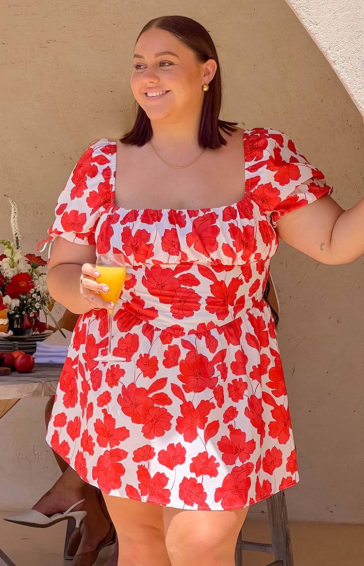 Ruched bodice of a white mini dress with red anemone floral print, featuring a square neckline and short puff sleeves