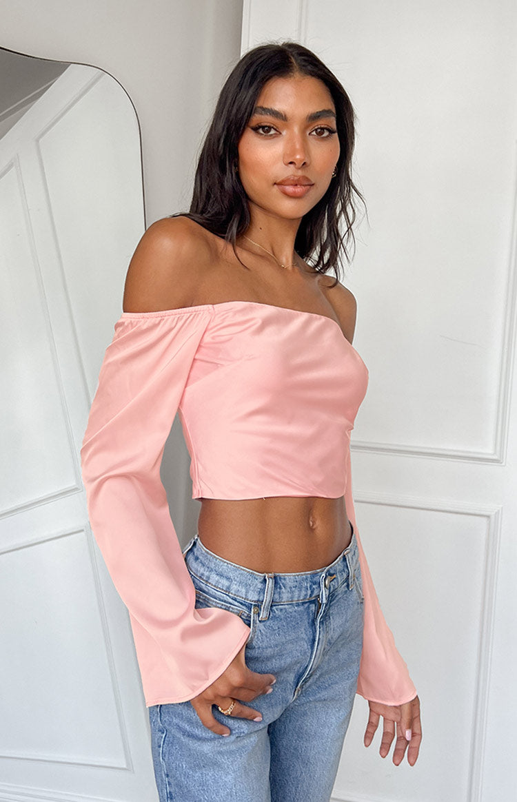 Front view of a pink satin off-shoulder crop top with elasticated neckline and long flared sleeves
