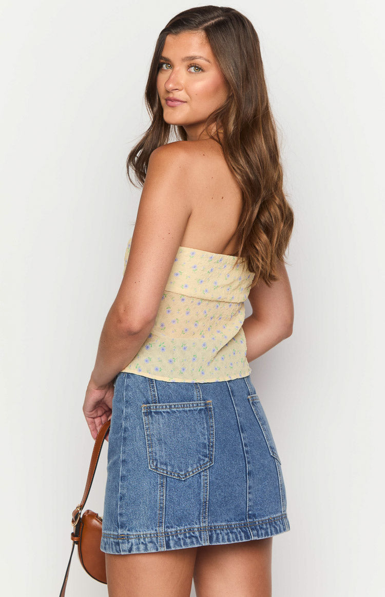 Side-rear view of a mid wash denim mini skirt with rectangular patch pockets and vertical seam detailing