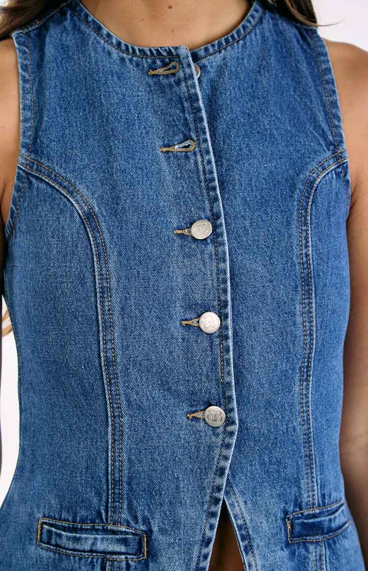 Close-up of the mid wash denim vest showing the button-down placket with silver buttons and contrast stitching