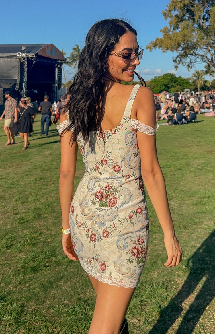 Rear and side view of a beige tapestry mini dress with red floral and blue paisley pattern, featuring lace trim on straps and hem