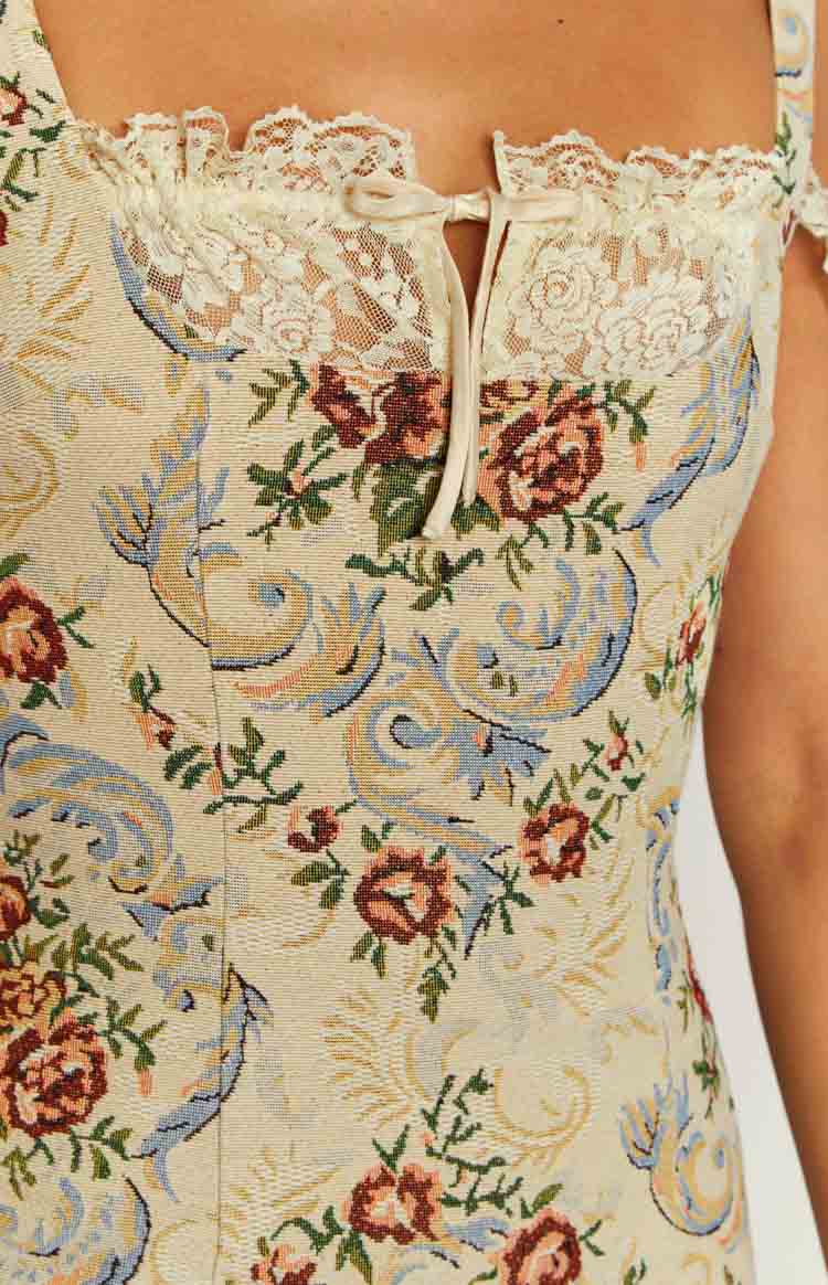 Close-up of the beige tapestry mini dress showing the floral pattern, lace trim, and front tie neckline