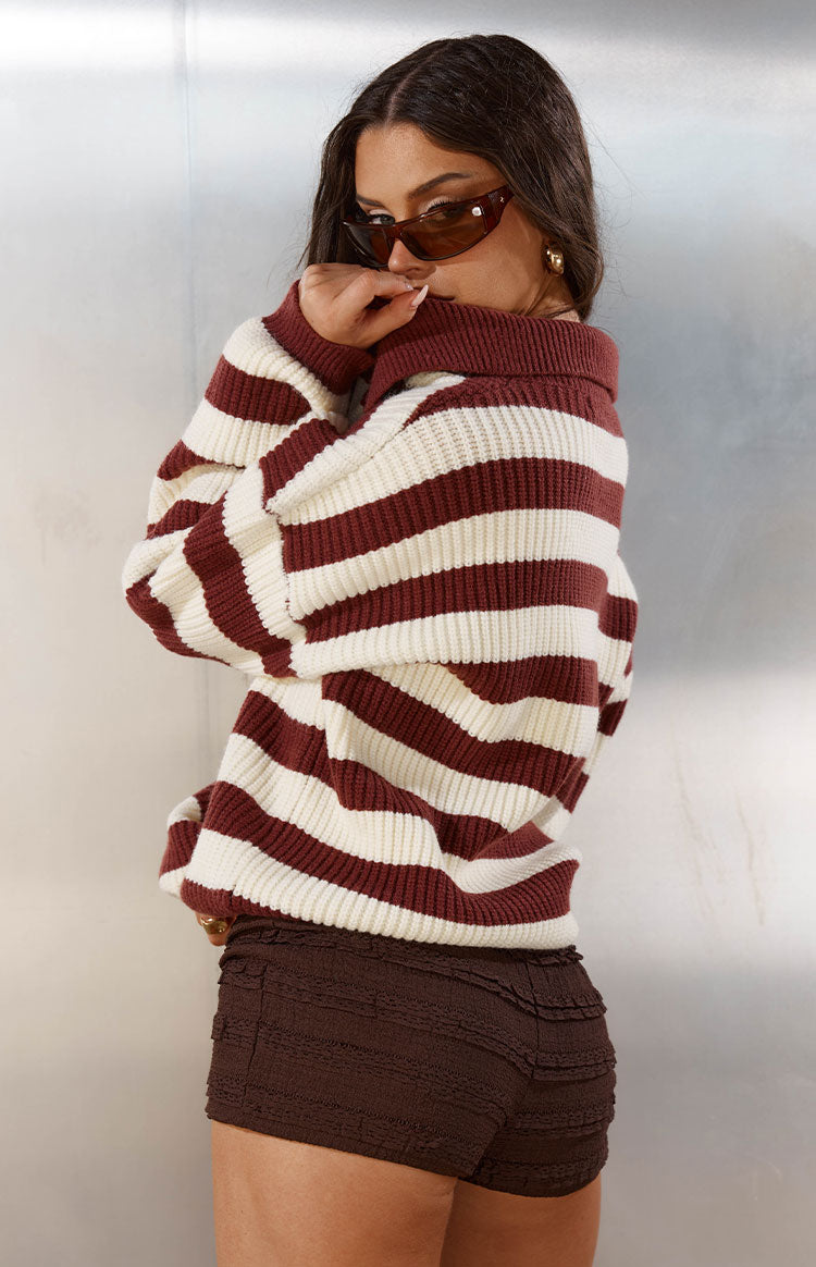 Side view of a burgundy and cream striped knit sweater with a relaxed fit and chunky ribbed texture