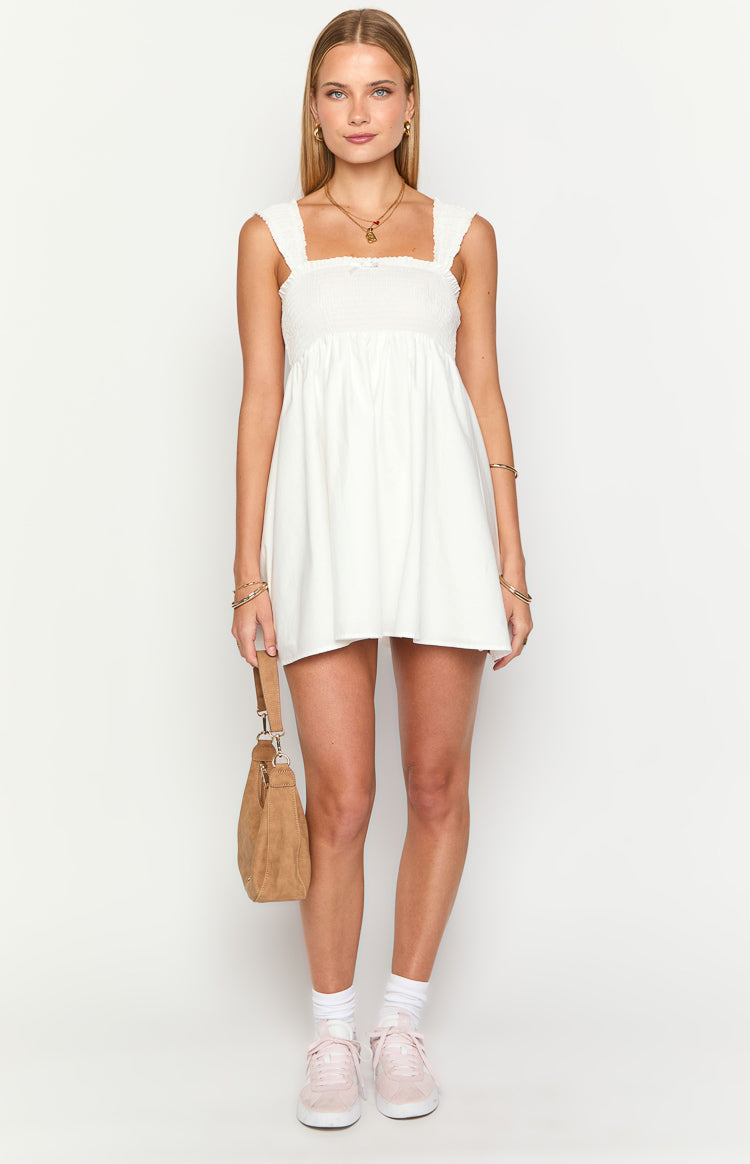White mini dress with smocked bodice, square neckline, cap sleeves, and a small bow