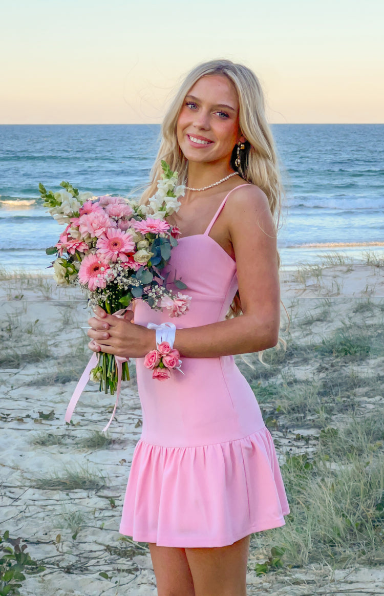 Side view of a pink crepe mini dress with thin spaghetti straps and a gathered ruffle skirt