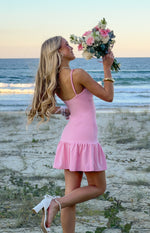 Side view of a pink crepe mini dress with thin spaghetti straps and a ruffled hem