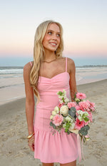 Pink crepe mini dress with a ruched bust, thin spaghetti straps, and a ruffled hem