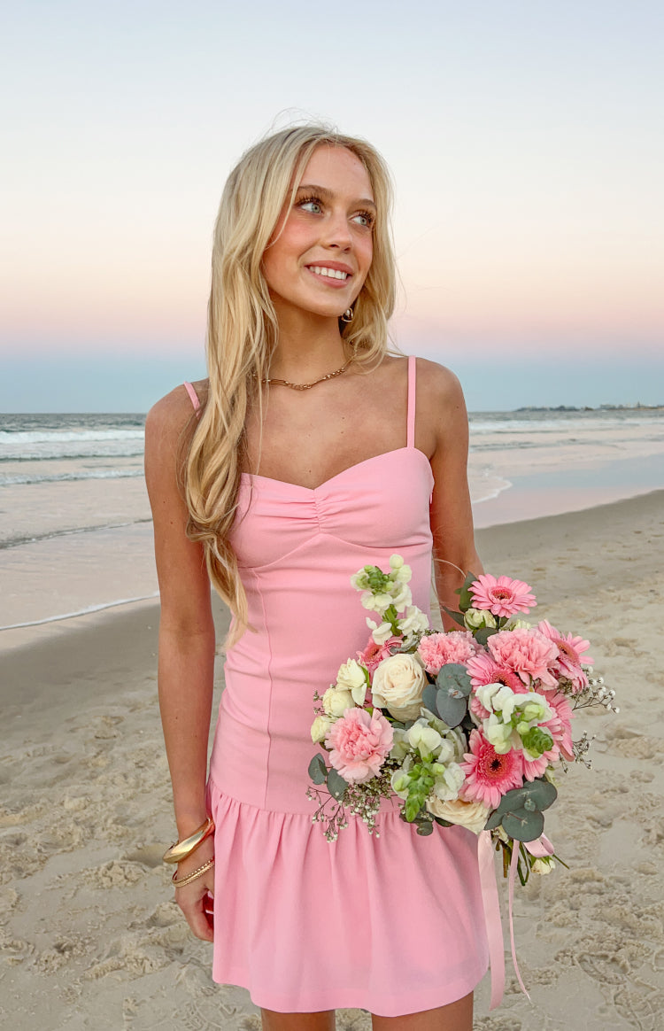 Pink crepe mini dress with a ruched bust, thin spaghetti straps, and a ruffled hem