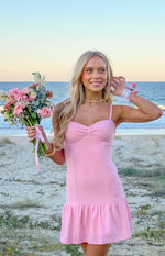 Pink crepe mini dress with a ruched sweetheart neckline, spaghetti straps, and tiered ruffle hem