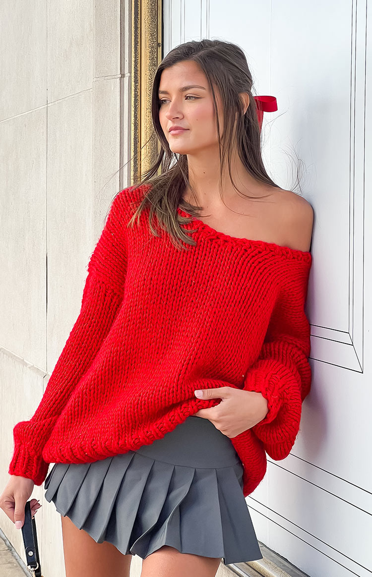 Red chunky knit sweater with an off-shoulder neckline and voluminous long sleeves
