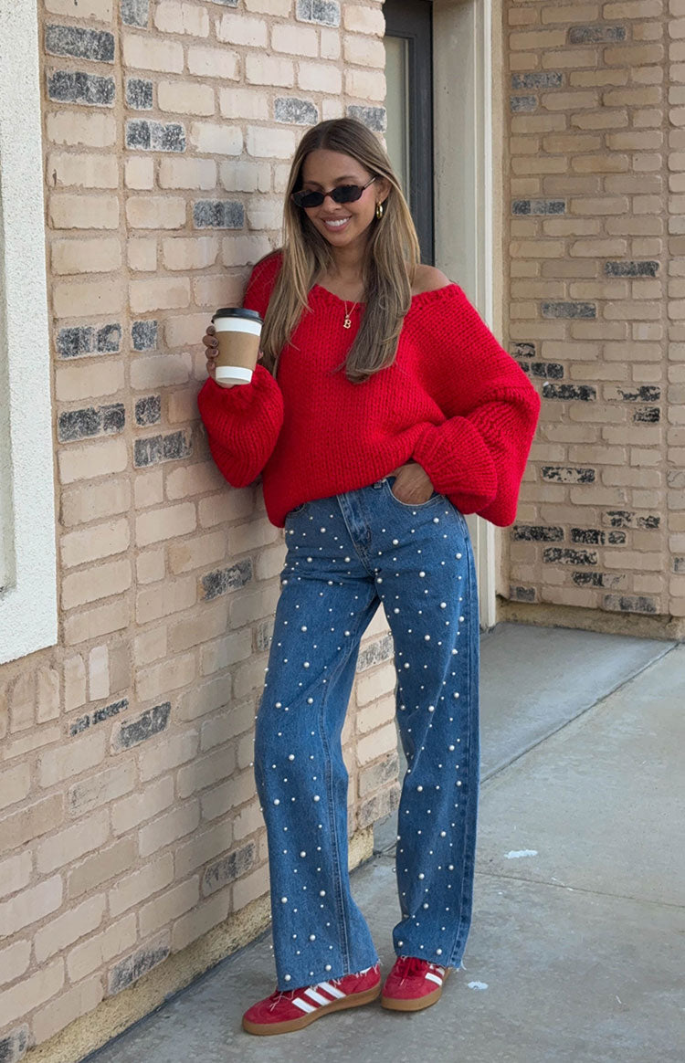 Red chunky knit sweater with an oversized fit and wide V-neck worn off-shoulder