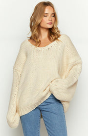 Cream chunky knit sweater with a wide V-neckline and oversized fit, showing the voluminous long sleeves