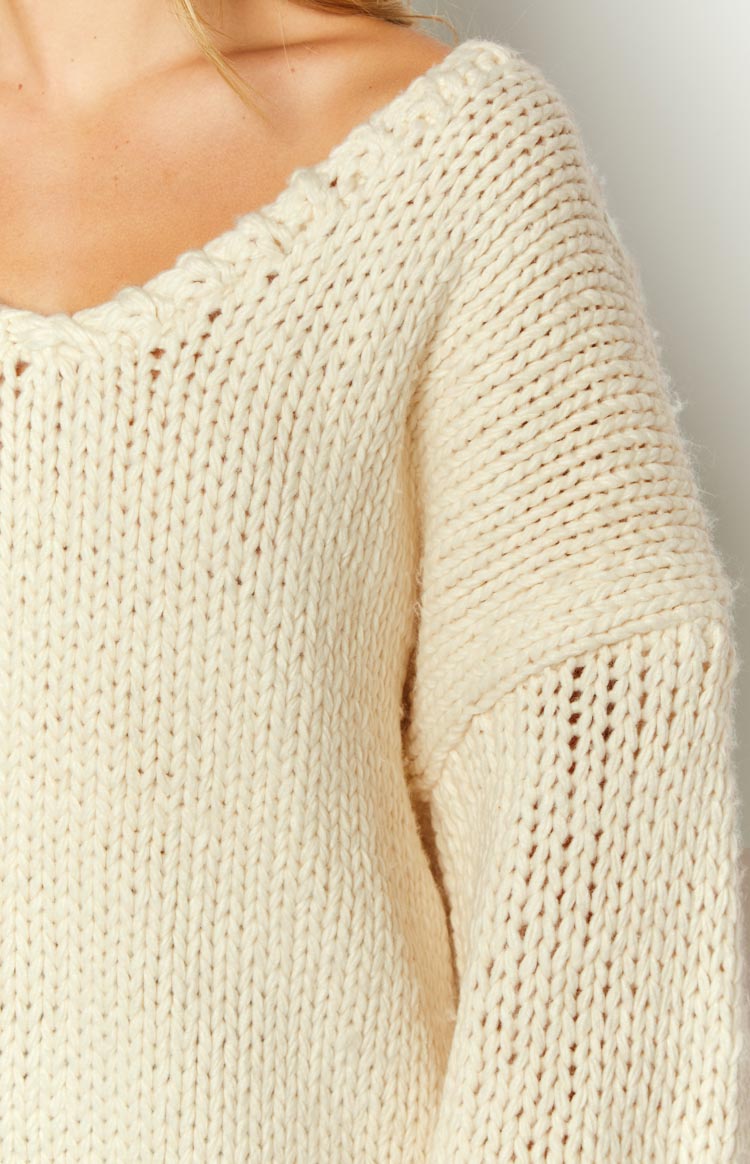 Wide open-knit neckline and dropped shoulder detail on a cream chunky knit sweater