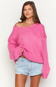 Hot pink chunky knit sweater with an off-shoulder neckline, wide sleeves, and visible chunky texture