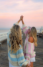 Rear and side view of a light blue and cream striped chunky knit sweater with relaxed fit and long sleeves