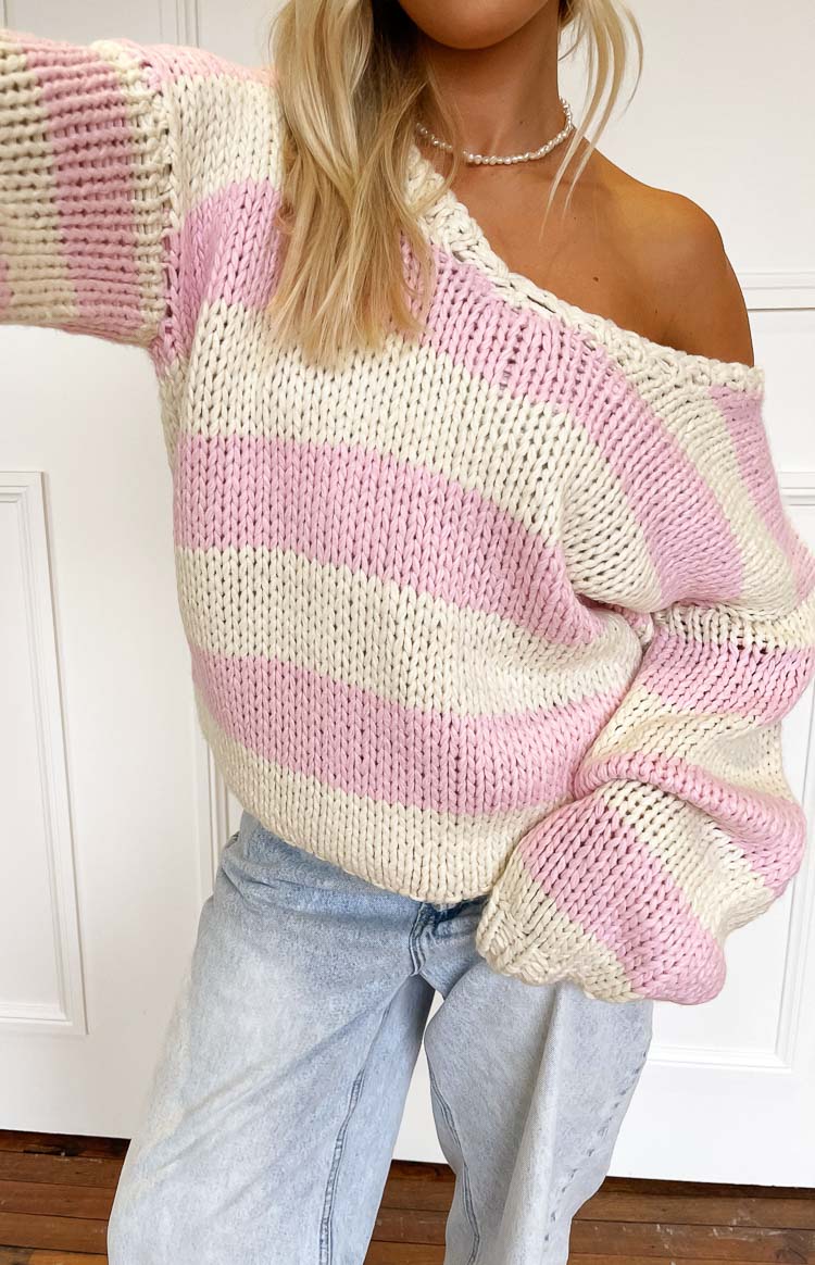 Close-up of the off-shoulder neckline and chunky knit texture of a pink and cream striped sweater